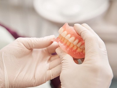 Gloved hands holding some removable dentures 