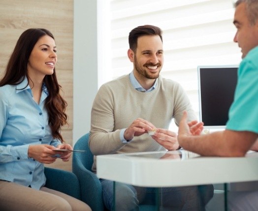 Two happy dental patients talking to dentist