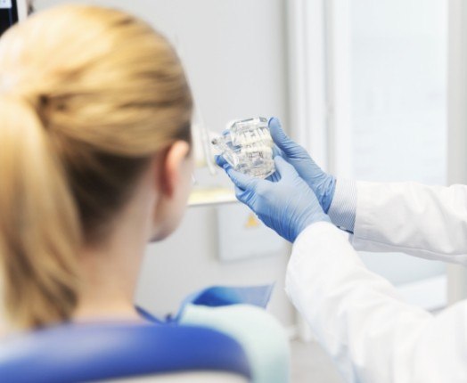 Dentist showing patient a smile model during preventive dentistry checkup and teeth cleaning visit