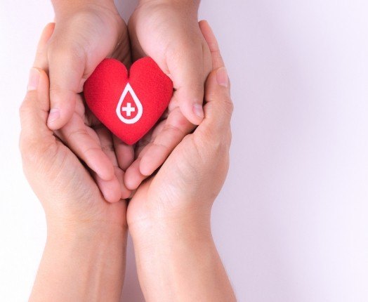 Hands holding red heart representing blood donation