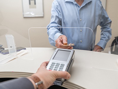 An adult man paying the cost of cosmetic dentistry