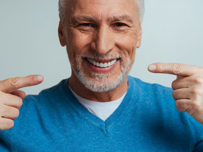 A happy older man pointing to his smile