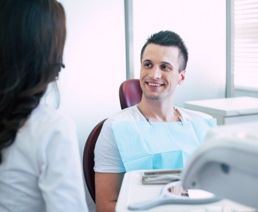 Man smiling at dentistry team member during dental checkup and teeth cleaning visit