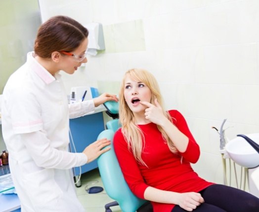 Woman pointing to mouth during tooth extraction consultation