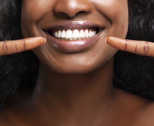 Woman pointing to healthy smile after gum disease treatment