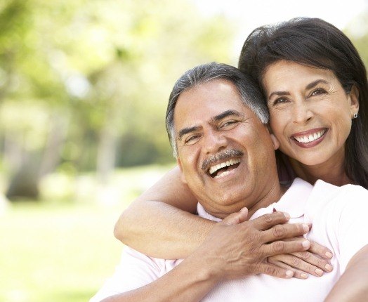 Smiling man and woman enjoying the benefits of dental implants