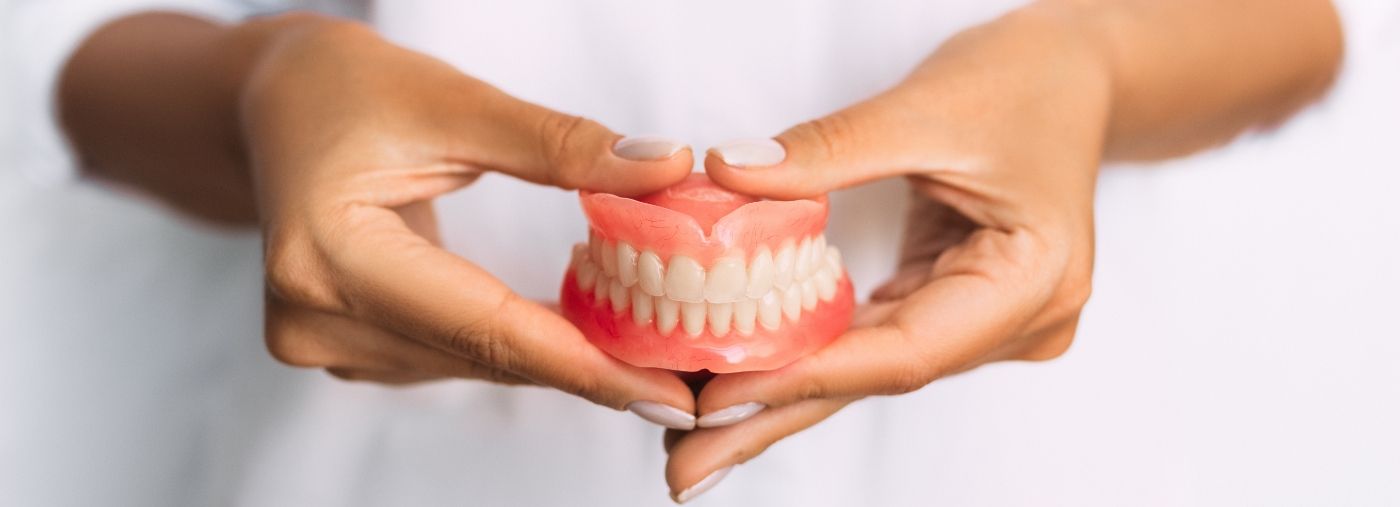 Dental insurance dentist holding full denture