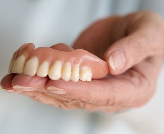 Hand holding full denture