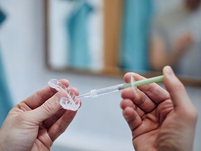 A young man preparing take-home teeth whitening trays