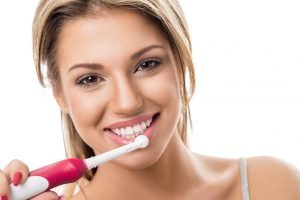 Smiling girl with electric toothbrush