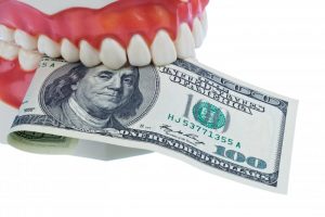 A denture holding a one-hundred dollar bill.