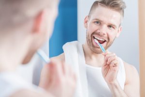 young man smiling brushing teeth