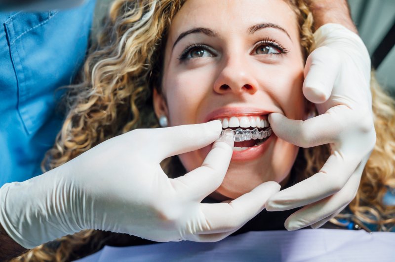 A dentist placing a clear aligner on a woman patient